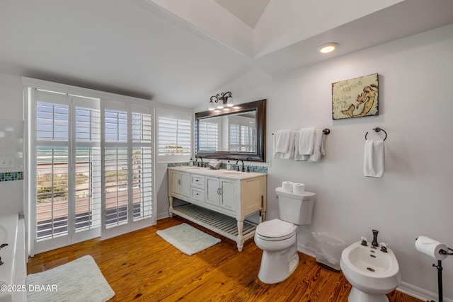 bathroom featuring vaulted ceiling, toilet, a sink, a bidet, and wood finished floors