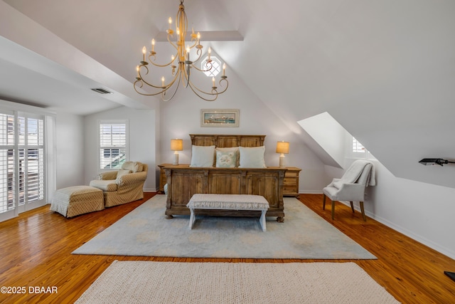 bedroom with an inviting chandelier, wood finished floors, lofted ceiling, and visible vents