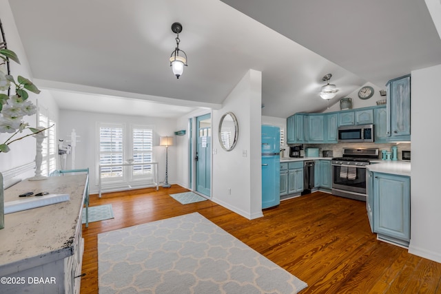 kitchen featuring blue cabinets, vaulted ceiling, light countertops, and appliances with stainless steel finishes