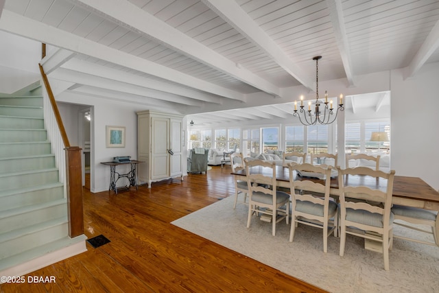dining area featuring beam ceiling, stairway, a chandelier, and wood finished floors