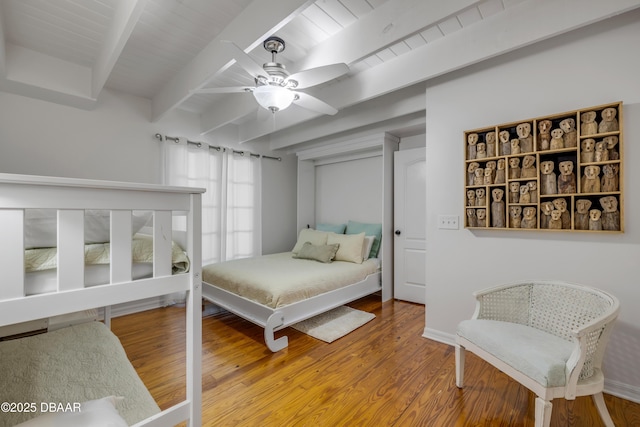 bedroom with beam ceiling, baseboards, ceiling fan, and wood finished floors