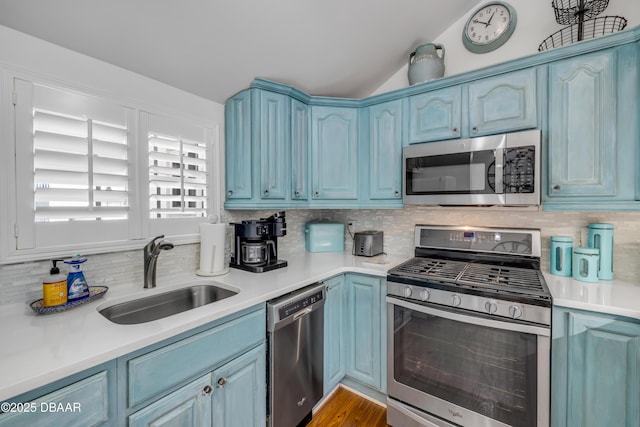 kitchen featuring blue cabinets, a sink, light countertops, and appliances with stainless steel finishes