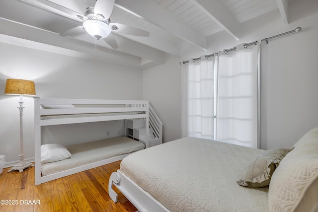 bedroom featuring ceiling fan, wood finished floors, and beam ceiling