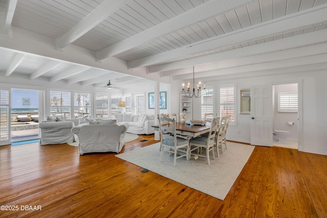 unfurnished dining area featuring wooden ceiling, ceiling fan with notable chandelier, baseboards, beam ceiling, and wood finished floors