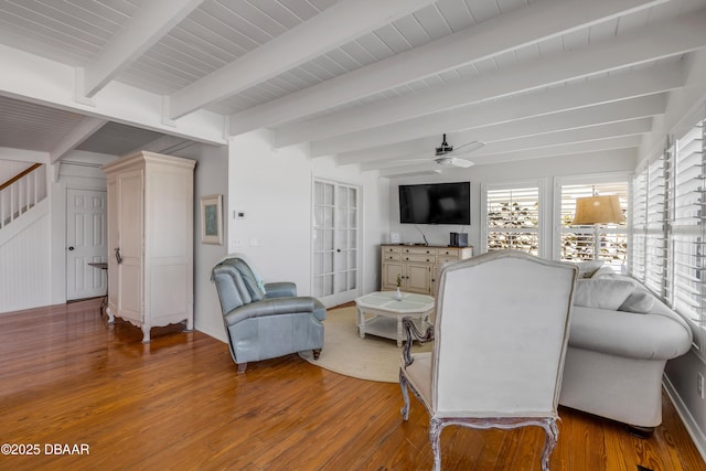 living room with light wood finished floors, beam ceiling, ceiling fan, and stairway