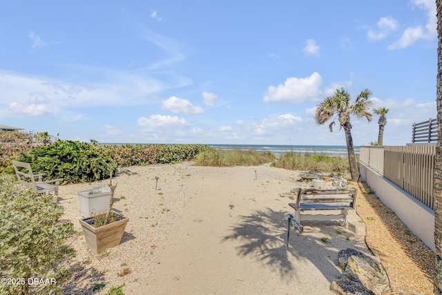 view of yard featuring a beach view, a water view, and fence