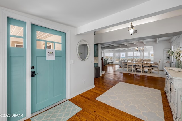foyer featuring baseboards, dark wood-style flooring, a notable chandelier, and beamed ceiling