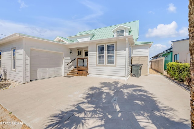 traditional-style home with concrete driveway, a garage, fence, and metal roof