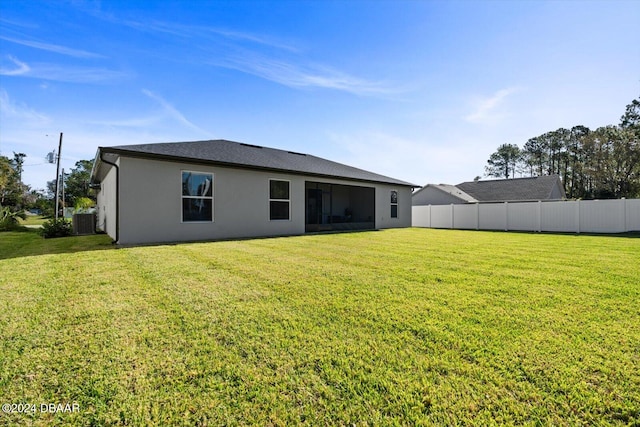 rear view of property featuring a yard and central air condition unit