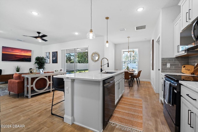 kitchen with black appliances, white cabinets, a center island with sink, and sink