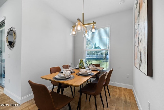 dining space with light hardwood / wood-style floors and an inviting chandelier