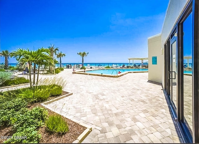 view of pool featuring a patio and a water view