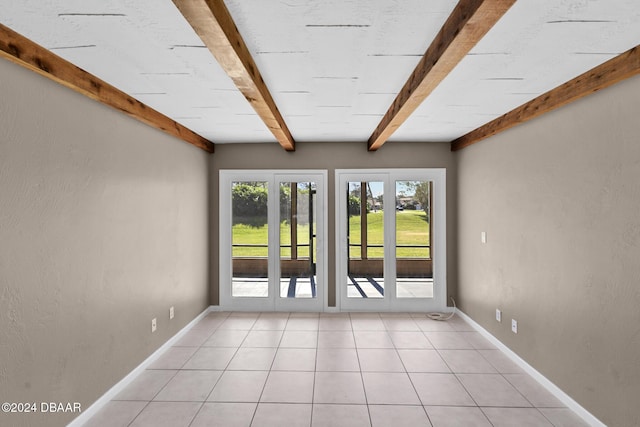 spare room with beam ceiling, french doors, and light tile patterned flooring