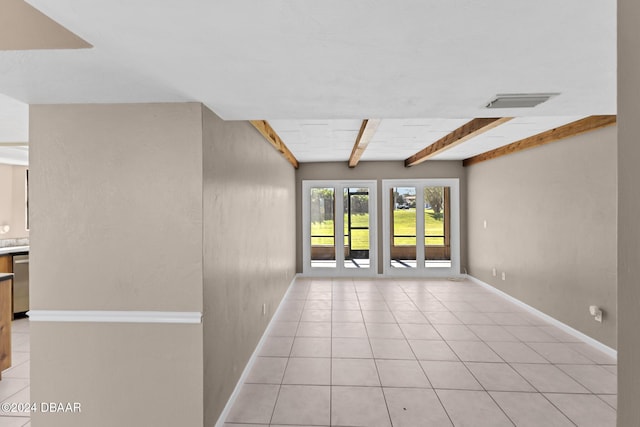 tiled empty room featuring beamed ceiling