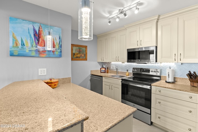 kitchen with appliances with stainless steel finishes, pendant lighting, sink, decorative backsplash, and cream cabinetry