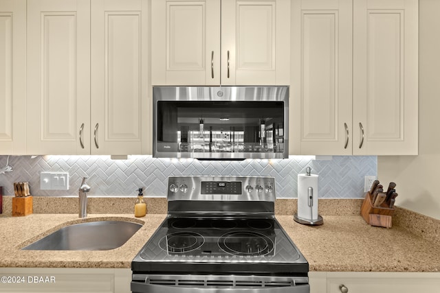 kitchen featuring decorative backsplash, stainless steel appliances, sink, and light stone countertops