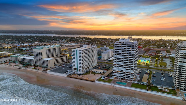 aerial view at dusk with a beach view and a water view