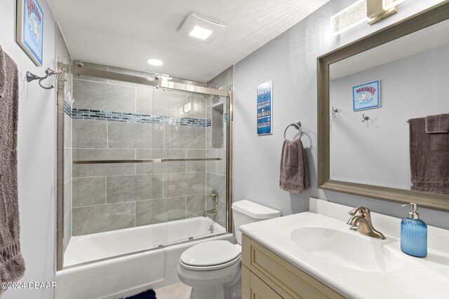 full bathroom with bath / shower combo with glass door, vanity, and toilet