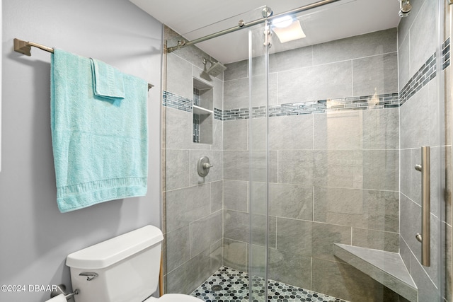 bathroom featuring toilet and a shower with shower door