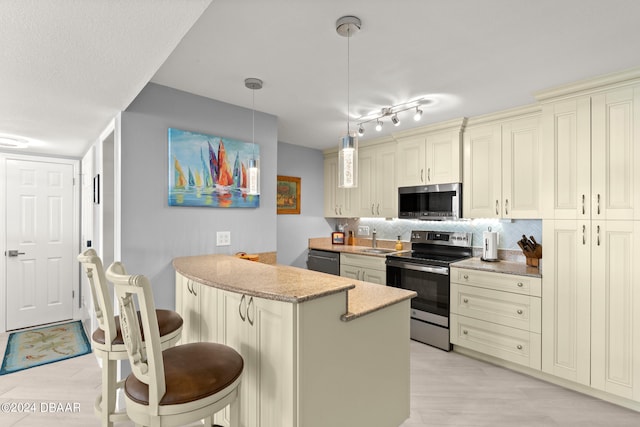 kitchen with stainless steel appliances, a breakfast bar, backsplash, hanging light fixtures, and cream cabinetry