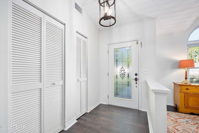 entryway with wood finished floors, visible vents, baseboards, ornamental molding, and a notable chandelier