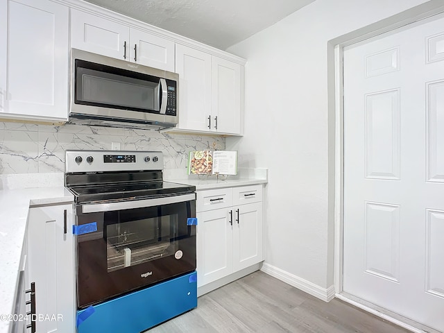 736 N Segrave St, Daytona Beach, FL 32114 - kitchen featuring white cabinetry, light wood-type flooring, appliances with stainless steel finishes, and tasteful backsplash