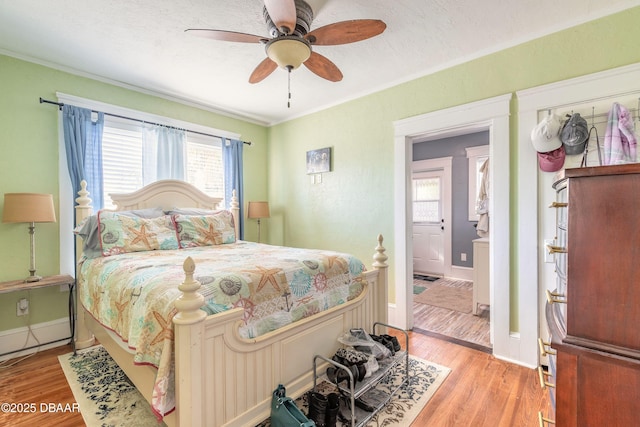 bedroom featuring light wood finished floors, crown molding, and baseboards
