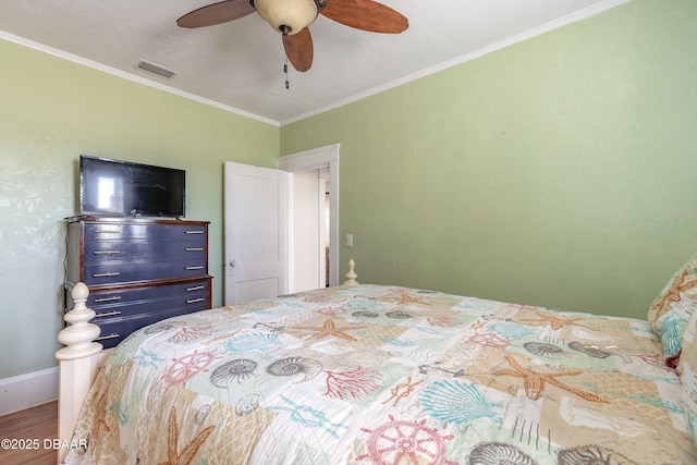 bedroom with visible vents, wood finished floors, crown molding, baseboards, and ceiling fan