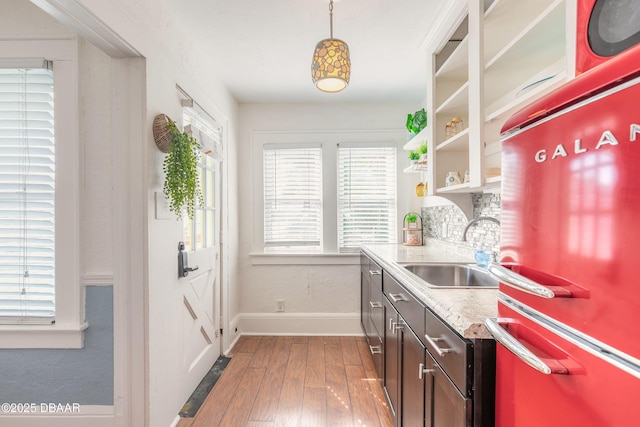 kitchen featuring a sink, baseboards, refrigerator, wood-type flooring, and open shelves