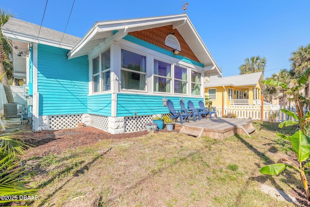 back of house with cooling unit, roof with shingles, a yard, a sunroom, and a deck