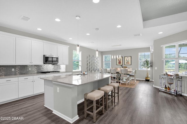 500 Barefoot Life Ln, Daytona Beach, FL 32124 - kitchen with stainless steel microwave, healthy amount of natural light, dark wood finished floors, an island with sink, and recessed lighting