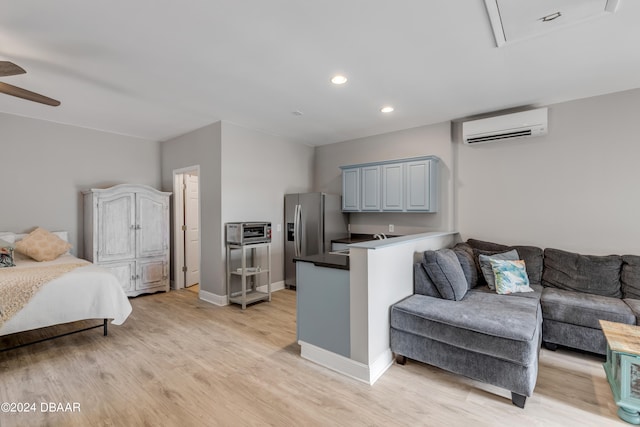 kitchen with a wall mounted AC, kitchen peninsula, ceiling fan, light wood-type flooring, and stainless steel fridge