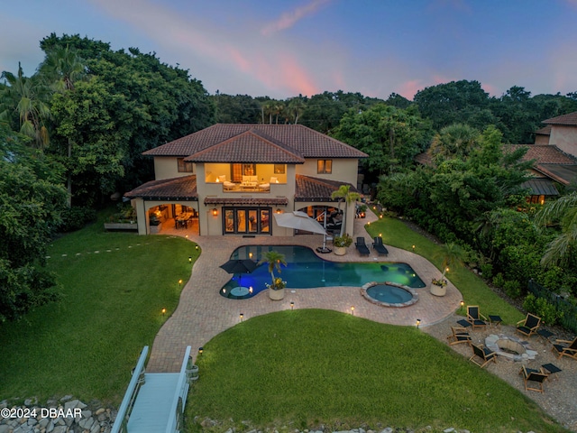 pool at dusk with a yard, a patio, a gazebo, and an in ground hot tub