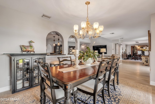 dining space with light wood-type flooring and a notable chandelier