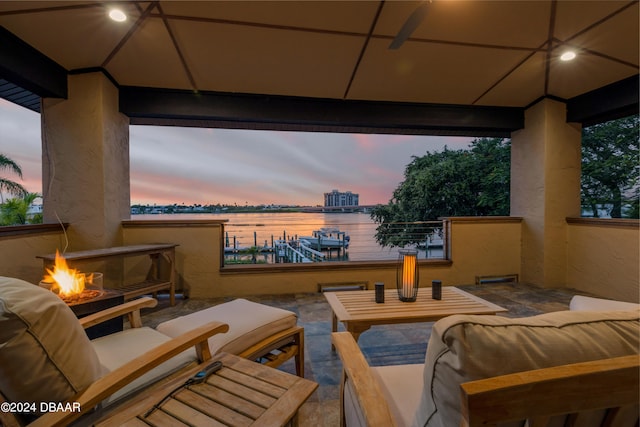 patio terrace at dusk with an outdoor living space with a fire pit, a water view, and a gazebo