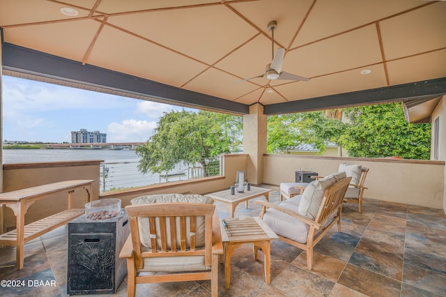 view of patio / terrace featuring a water view, ceiling fan, and an outdoor living space with a fire pit