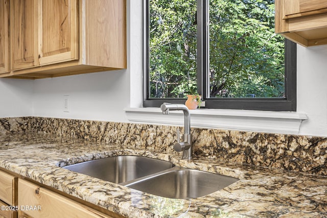 interior details featuring light stone counters, a sink, backsplash, and light brown cabinets