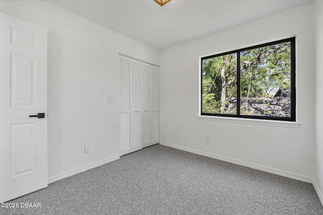 unfurnished bedroom featuring baseboards, carpet floors, and a closet