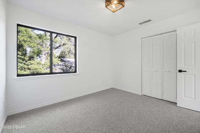 unfurnished bedroom featuring visible vents, baseboards, multiple windows, and carpet floors