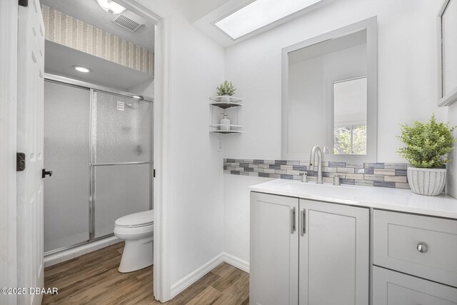 bathroom featuring a shower stall, visible vents, toilet, wood finished floors, and backsplash