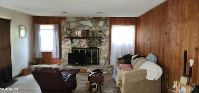 living room featuring a stone fireplace and wooden walls