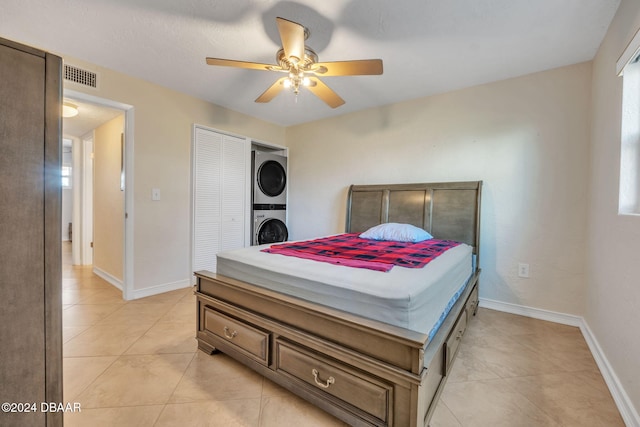 bedroom featuring stacked washing maching and dryer, ceiling fan, and light tile patterned floors