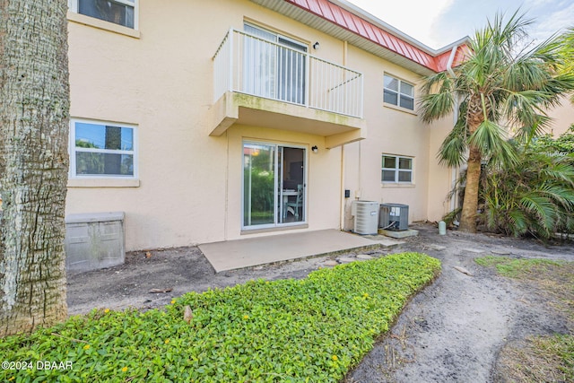 back of property featuring central AC unit, a patio, and a balcony