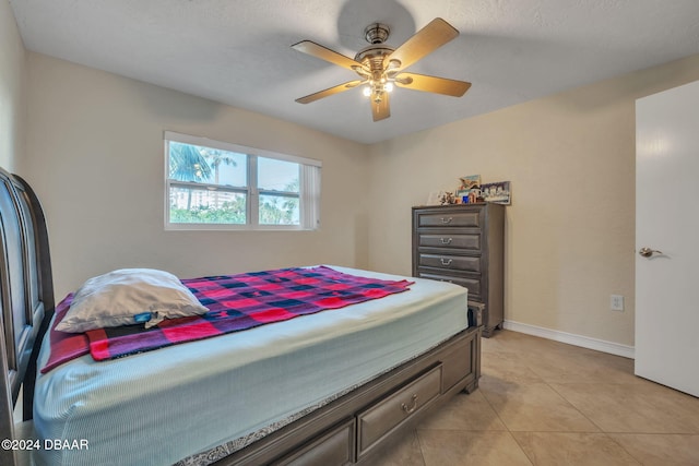 bedroom with a textured ceiling, light tile patterned floors, and ceiling fan