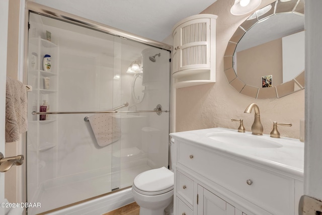 bathroom with toilet, vanity, and a shower with shower door