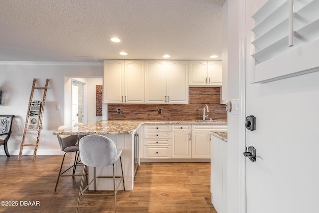 kitchen with light wood finished floors, a breakfast bar, backsplash, and a sink