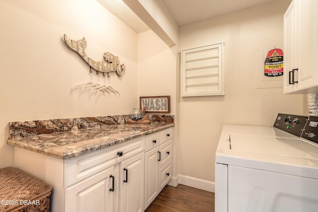 washroom featuring dark wood-style flooring, washing machine and dryer, cabinet space, and baseboards