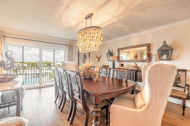 dining space featuring a chandelier, ornamental molding, a textured ceiling, and light wood-style flooring