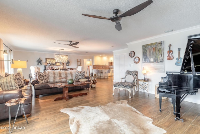 living room featuring crown molding, a textured ceiling, wood finished floors, and ceiling fan with notable chandelier