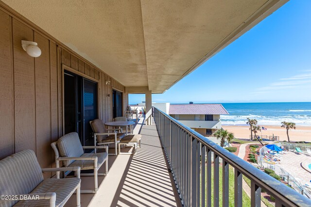 balcony featuring a view of the beach and a water view